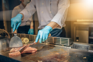 Hand of man take cooking of meat with vegetable grill, Chef cooking wagyu beef in Japanese teppanyaki restaurant