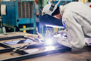 Industrial worker in manufacturing plant grinding to finish a Metal pipe,Industrial Worker at the factory welding closeup