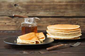 puncakes with honey and cup of tea on old wooden background