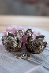 two silver swans, two wedding rings and flowers on a linen napkin on the table