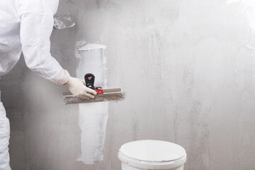 the master applies a mortar to the wall with a spatula to level them, on the right is a place for...