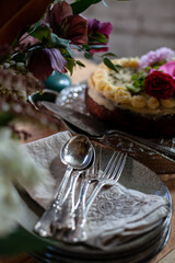 birthday or wedding cake, retro plates, forks, spoons, napkins, flowers on a wooden table