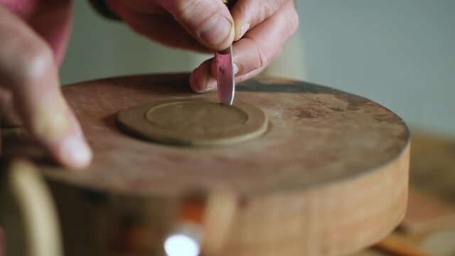 a potter carves a circle out of clay with a knife. pottery art concept. handmade pottery. a potter makes a clay product
