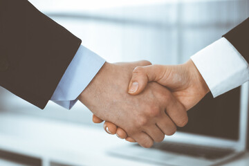 Businessman and woman shaking hands in office. Concept of handshake as success symbol in business