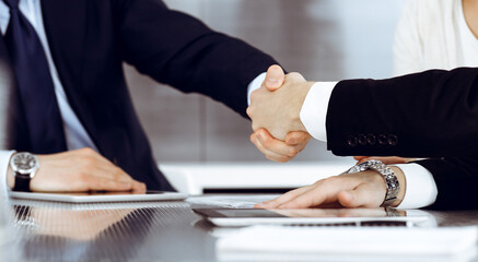 Business people shaking hands after contract signing in modern office. Teamwork and handshake concept
