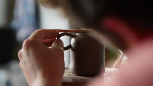 a professional potter sets the level of the handle to the clay teapot. Craft production of devices for tea ceremony