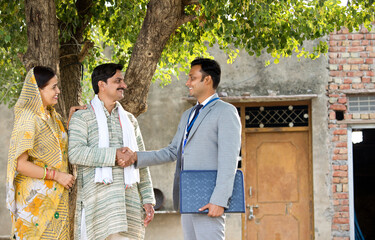 Rural Indian couple with farmer and bank executive shaking hands in village