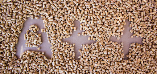 Renewable wood heating pellets with letter A and plus plus sign for the reduce consumption on brown background. Top view. Wooden pellets background