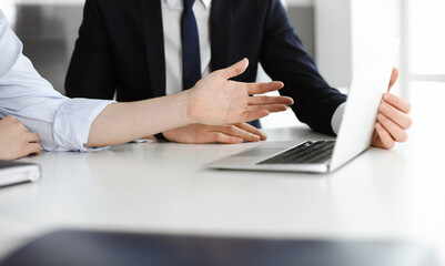 Fototapeta premium Unknown business people using laptop computer at the desk in modern office. Businessman or male entrepreneur is working with his colleague. Teamwork and partnership concept