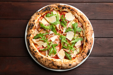 Tasty pizza with meat and arugula on wooden table, top view