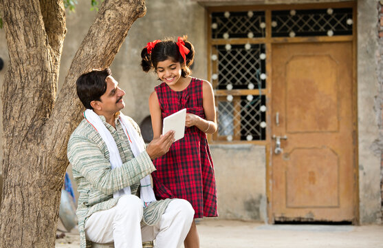 Rural girl with father using digital tablet at village