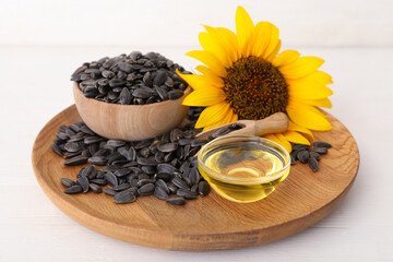 Fototapeta na wymiar Sunflower, oil in glass bowl and seeds on white wooden table