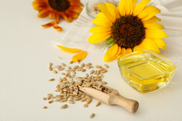 Sunflower oil in glass bowl and seeds on white table