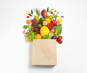 Paper bag with assortment of fresh organic fruits and vegetables on white background, top view