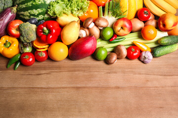 Assortment of fresh organic fruits and vegetables on wooden table, flat lay. Space for text