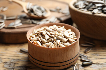 Peeled sunflower seeds in bowl on wooden table