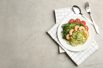 Delicious zucchini pasta with shrimps, cherry tomatoes and arugula served on light table, flat lay. Space for text
