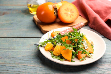 Delicious persimmon salad served on light blue wooden table
