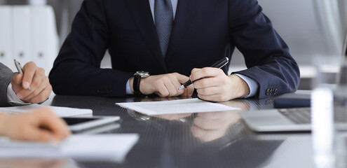 Unknown business people working together at meeting in modern office, close-up. Businessman and woman with colleagues or lawyers discussing contract at negotiation