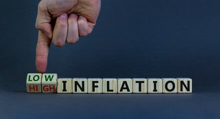 Low or high inflation symbol. Male hand turns cubes and changes words 'high inflation' to 'low inflation'. Beautiful grey background. Business and low inflation concept. Copy space.