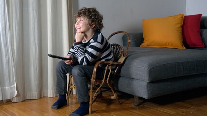 Europe, Italy , MIlan - Child boy 6 years old watching television and playing video games with mask during Covid-19 Coronavirus lockdown quarantine home 