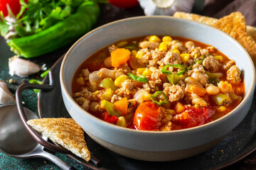 Traditional mexican food. Chili con carne close-up, minced meat with vegetables on dark stone table.