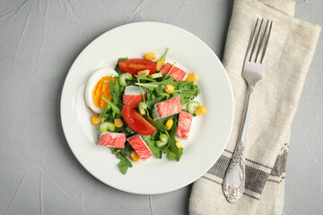 Delicious crab stick salad served on grey table, flat lay