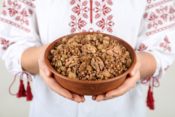 Woman in slavic shirt holding bowl with traditional kutia, closeup