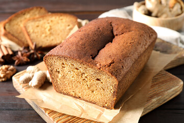 Delicious gingerbread cake and ingredients on wooden table, closeup
