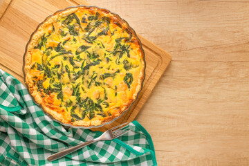Salmon fish and baby spinach leaves quiche pie - homemade recipe pie on wooden table background with copy space, selective focus. Top view