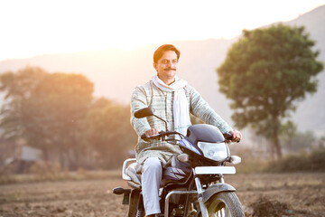 Happy rural Indian man riding on motorcycle in village