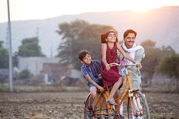 Happy rural Indian farmer with children riding on bicycle