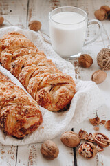 Fresh homemade cakes are on the table. the cup is filled with milk. nearby are walnuts. A soft picture.