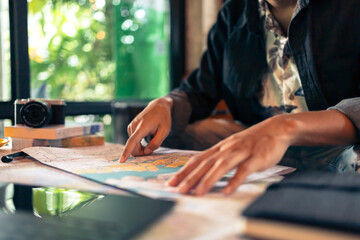 Fototapeta premium Tourist planning vacation with map and other travel accessories on the table. Travel, holiday, vocation concept.