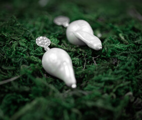 handmade pearl earrings on the forest floor in the green grass