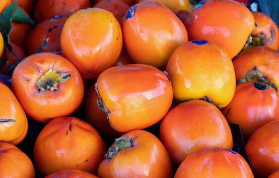 A group of orange persimmons at a small city market.
