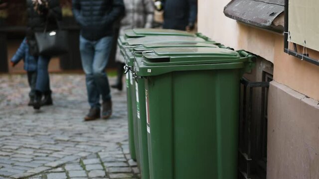 Green trash bins for trash recycling with group of people passing by