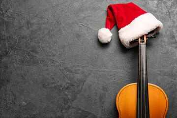 Violin with Santa Claus hat on dark background