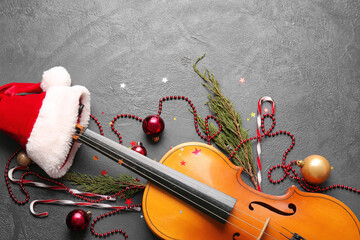 Fototapeta na wymiar Violin with Santa Claus hat and Christmas decor on dark background