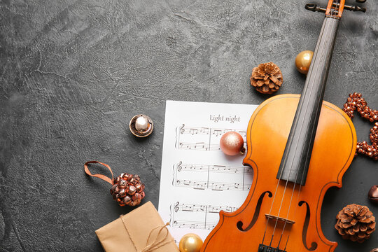 Violin with Christmas decor and music notes on dark background