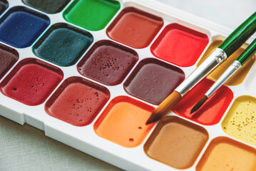 box of new watercolor paints and two paintbrushes closeup