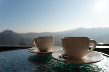 picture of two coffee cup on table with mountain view in morning. couple together and relationship concept
