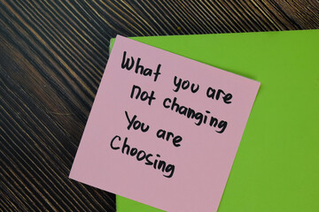 What you are not changing you are choosing write on sticky notes isolated on Wooden Table. Motivation concept