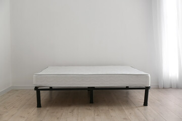 Bed with comfortable orthopedic mattress in room