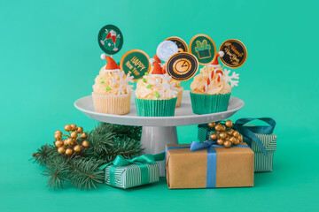 Dessert stand with tasty Christmas cupcakes on color background