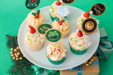 Dessert stand with tasty Christmas cupcakes on color background