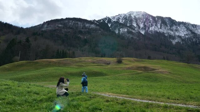 Mother Takes Pictures Photo on Smartphone of Little Child on Grass near Scenic Mountain Peak Stanserhorn. Ennetmoos Switzerland Europe