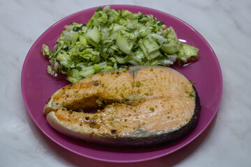 Grilled salmon steak with cabbage and cucumber salad. Keto diet dish.
