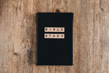 Bible Study in block letters on a bible on a wooden table. Top view flat lay.