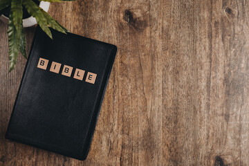 Word Bible in block letters on a bible on a wooden table.Top view flat lay.
